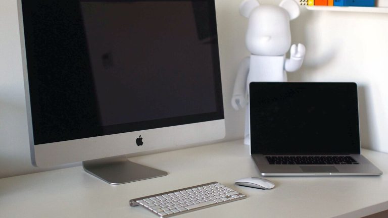 책상 위에 iMac 한 대와 MacBook 한 대가 나란히 놓여 있는 작업 공간