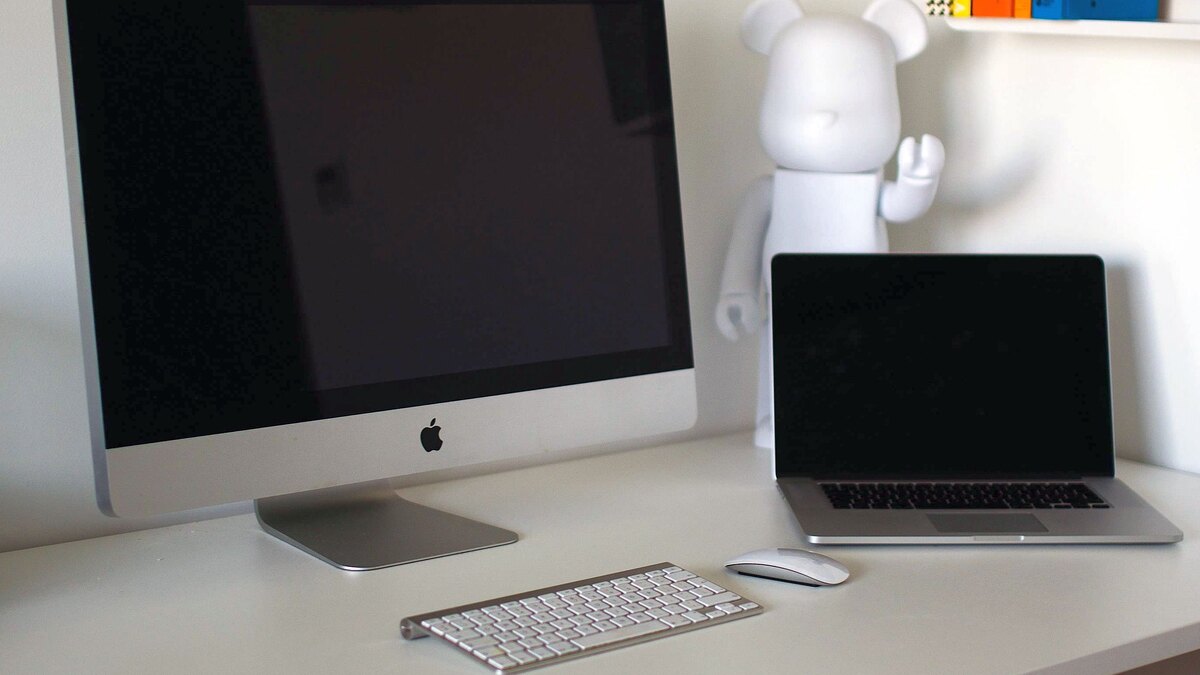 책상 위에 iMac 한 대와 MacBook 한 대가 나란히 놓여 있는 작업 공간